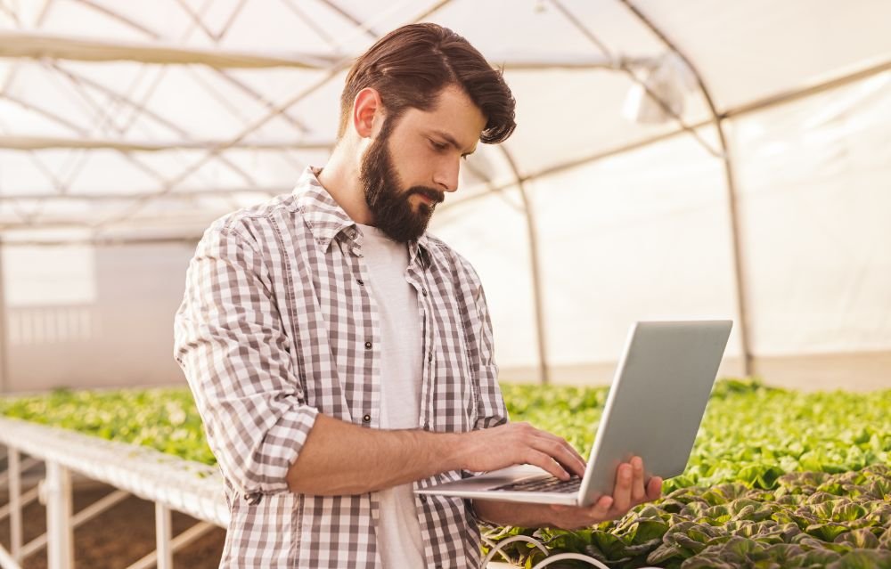 Bearded Gardener Browsing Laptop Near Hydroponic T 2EH4X9T